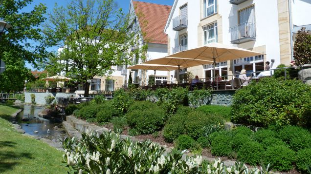 Das Bild zeigt Gastronomien und eine kleine Grünanlage entlang der Ems in Rietberg