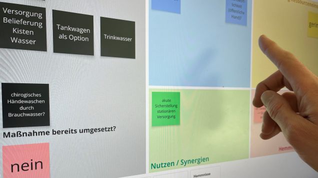 Hand wählt vor einem Bildschirm aus verschiedenen Optionen aus.