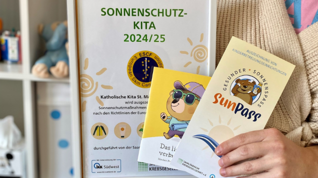 Person hält Bilderrahmen und zwei Prospekte in der Hand.