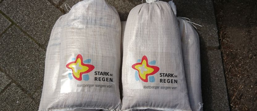 Foto von Sandsäcken mit aufgeklebten Projektlogo für den Hochwasserschutz 