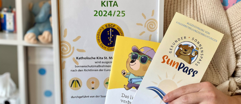Person hält Bilderrahmen und zwei Prospekte in der Hand.