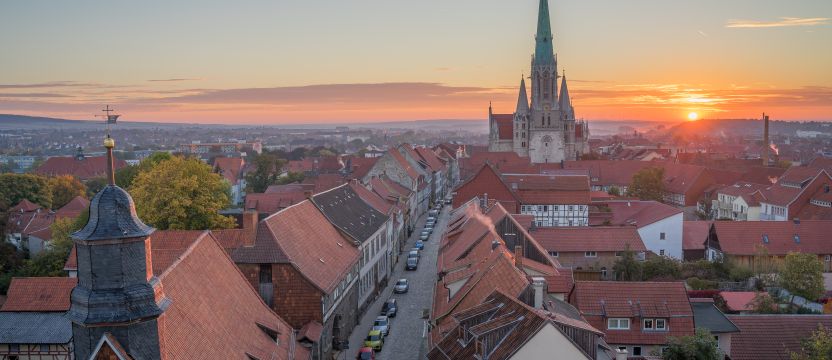 Zu sehen ist eine altertümliche Stadt mit Kirchturm bei Sonnenuntergang.