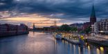 Zu sehen ist zentral der Fluss Weser. Dieser ist gerahmt von Gebäuden links und rechts. Die rechte Seite stellt den Beginn der Bremer Innenstadt dar, die Schlachte, die durch hohe Kaimauern und anliegenden alten Segelschiffen charakterisiert ist.