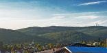 Hinter einem Hausdach mit solaranlagen erstreckt sich der Taunus: Mittelgebirge mit bewaldeten Hügeln.