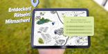 Eine Grafik einer Hand, die ein Tablet hält. Auf dem Tablet ist eine interaktive Karte mit Informationsfeldern gezeigt. Neben dem Tablet steht: Entdecken, Rätseln Mitmachen!