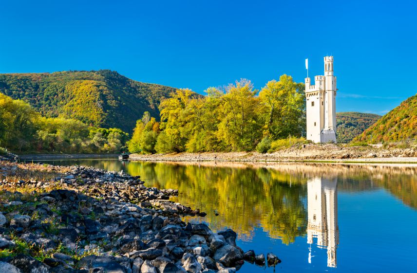 Der Maus Turm im Rhein bei Bingen Weißer Turm auf einer Insel im Fluss. Im Vordergrund Kiesstrand.