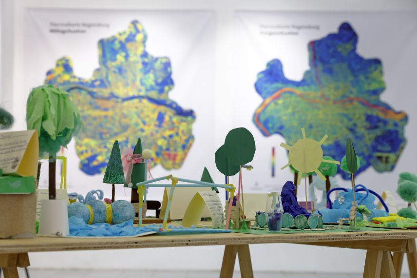 Modell des Platzes gebastelt aus einfachen Materialien. Im Hintegrund hängen Klimaanalysekarten aus.