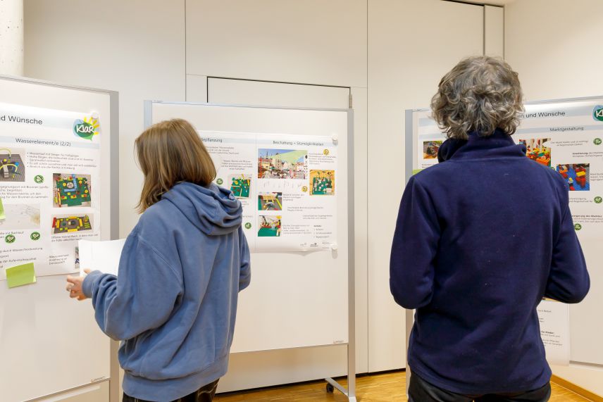 Bürgerinnen stehen vor ausgehängten Plakaten.