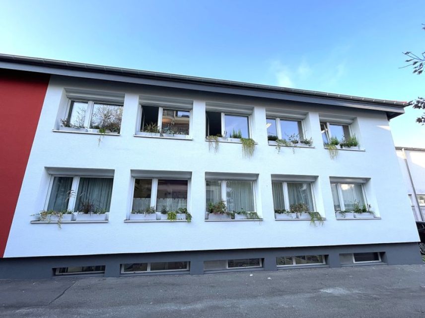 Zu sehen ist die Fensterseite eines weißen Hauses mit zwei Stockwerken.